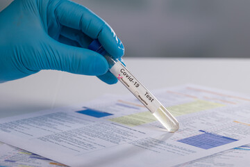 a hand in medical gloves is handling a positive coronavirus probe in front of a request form for...