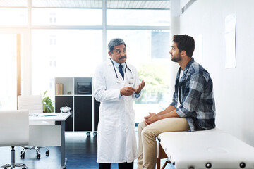 What seems to be the matter sir. Shot of a mature male doctor and patient having a discussion in the doctors office before a checkup.