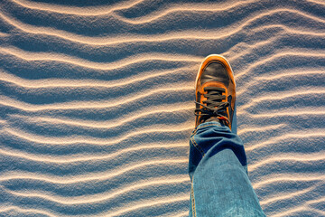 The shoe of a man standing on a sand dune - obrazy, fototapety, plakaty