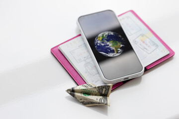 Passport with stamps, smartphone, plane made of one dollar bill.