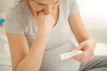 Pregnant woman making test. Close up of fingers holding express antigen covid corona test, positive...