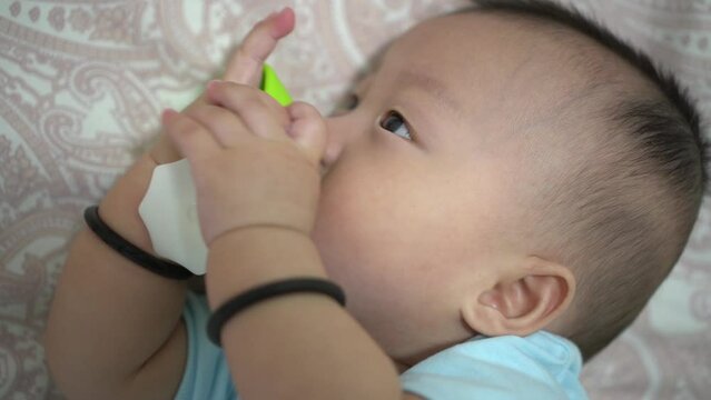 Cute infant put the green teether into the mouth