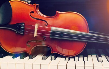 Fototapeta premium Violin on top of piano keyboard background for music concept