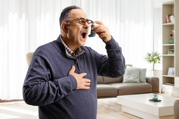 Mature man using an inhaler at home
