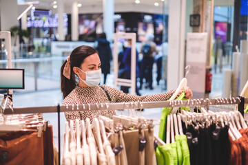 Young female customer examining green sweater in womens cloths store