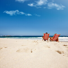 Getting away from it all. Rearview shot of an affectionate couple reclining on their deck chairs at the waters edge.