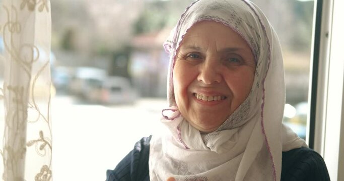 An old Turkish woman is wearing headscarf, hijab. Smiling to camera, Portait of muslim retired woman. Islamic culture, old woman is praying concept.