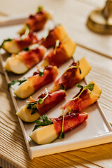 Appetizer with pear, blue cheese and prosciutto ham for holidays on a white plate.