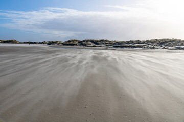 Sand fegt über den Strand bei Sturm und erzeugt ein Wellenmuster