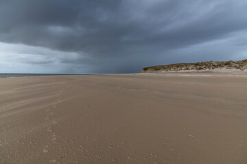 Fototapeta na wymiar endlose Weite am Sandstrand mit dunklen Regenwolken