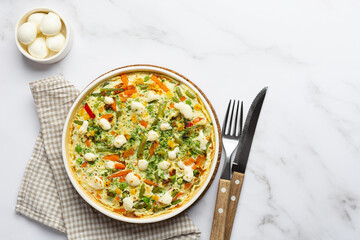 Top view egg frittata omelet with seasonal vegetables and cheese in plate on white marble...