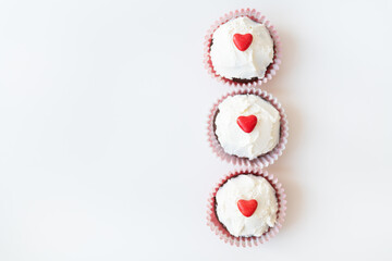 Valentine-14 February. Sweet chocolate muffins with butter cream and a red heart for decoration on a white background.