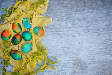 Fototapeta na wymiar Multi-colored Easter eggs and green branches on a blue background. Top view, copy space