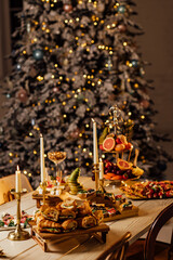beautifully decorated Christmas table with candles and glasses near the Christmas tree