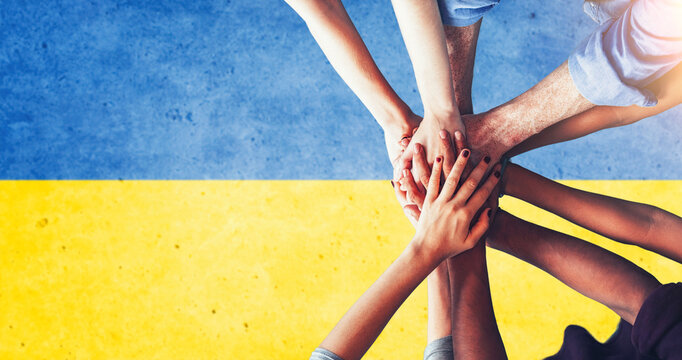 Ukraine people putting their hands together over the national flag of Ukraine, in demonstration of union against the war escalation. Resistance of the Ukrainian people to the war against the Russia.