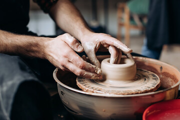 Fototapeta na wymiar A potter on a potter's wheel makes a jug