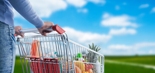 Woman pushing a shopping cart and blue sky