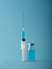 Vaccine and syringe injection on blue background. Vertical compozition