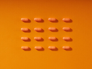 Pills in a row on orange background. Horizontal composition..