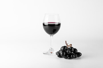 Red wine in glasses with grapes on white background.