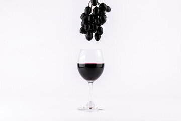 Red wine in glasses with grapes on white background.
