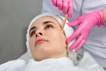Thread lifting. Tightening of flabby skin in the jaw area with the help of cosmetic threads. The doctor prepares the patient for the procedure by drawing stripes with a white pencil