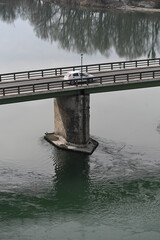 white car driving on a river brigde 
