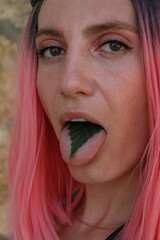 girl with pink hair shows tongue. on the tongue of a leaf