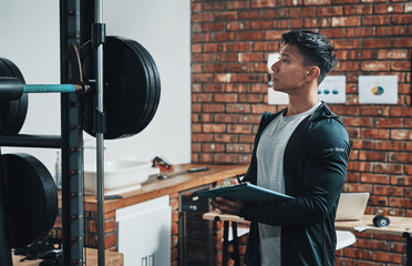 Just making sure everythings in good state. Cropped shot of a handsome young male fitness instructor inspecting exercise equipment while working in a gym.