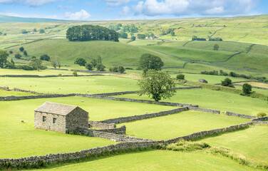 A view of an old stone barn and the rolling landscape of the Yorkshire Dales.