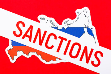 Paper with inscription Sanctions on map and flag of Russia due to aggressive foreign policy -...