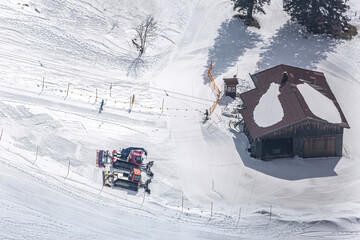 Ski slope scenery: skier and snow groomers at a ski lift from birds eye view