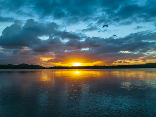 Sunrise, sunrays and rain clouds waterscape