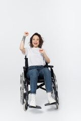 Excited woman in wheelchair showing yes gesture on grey background.
