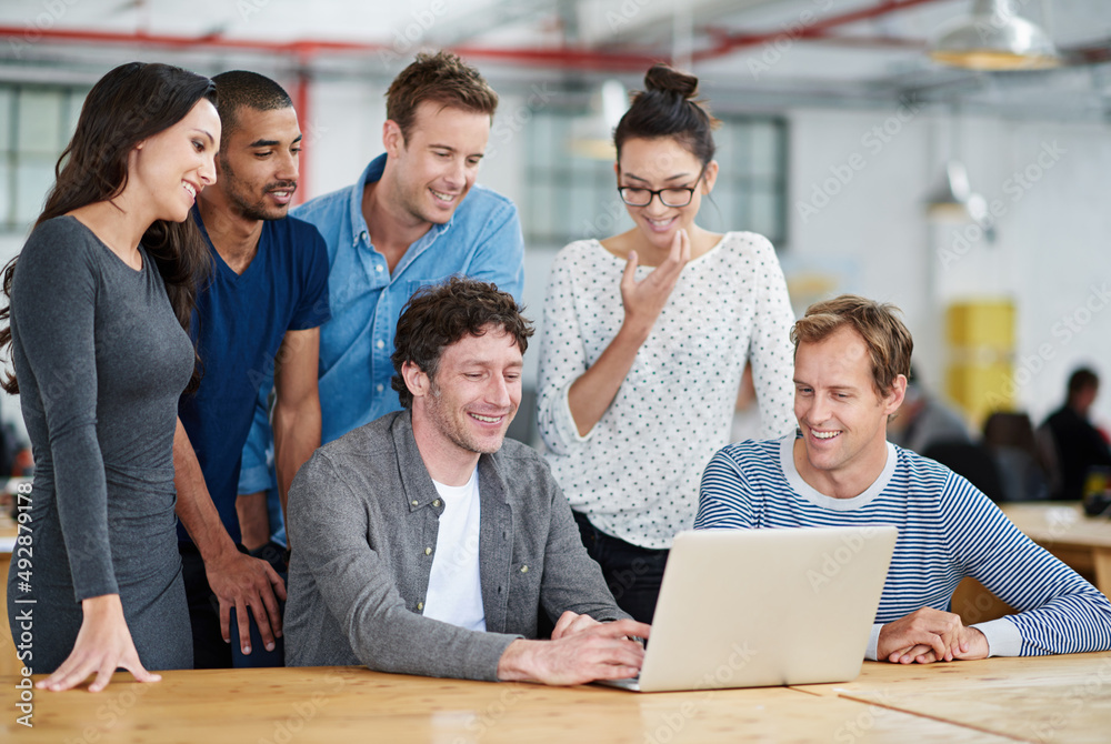 Poster technology is also part of their team. shot of a group of colleagues using a laptop together in a ca