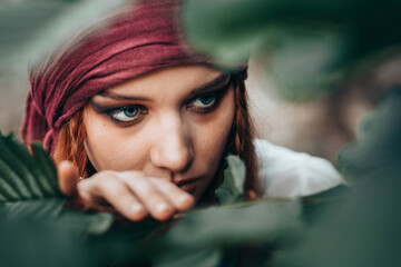 Portrait of young female in pirate costume peaking through branches