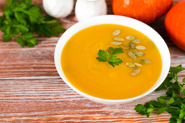 Delicious cream pumpkin soup on the wooden table. Preparing food from seasonal vegetables. Close-up. Copy space.