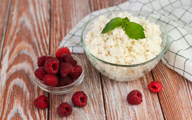 Delicious cottage cheese and ripe raspberries on the wooden table. Healthy breakfast. Close-up.