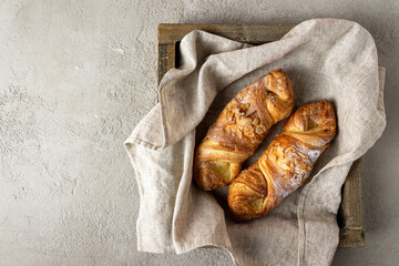 two buns with almonds lie on a linen napkin in a square wooden box, copy space