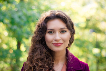 Fototapeta premium Beautiful woman in autumn park. Face close-up. Curly hair. The young woman smiles.