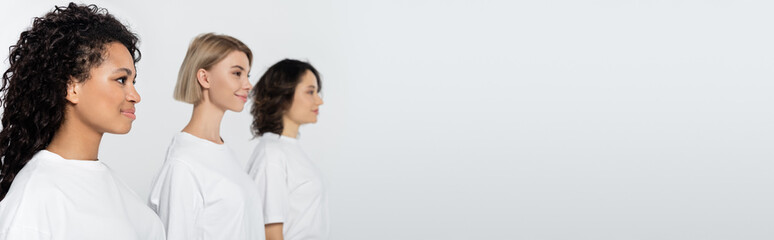 Positive african american woman standing near blurred friends isolated on grey, banner.