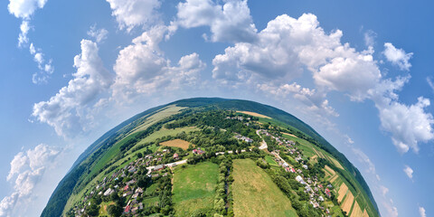 Aerial view from high altitude of little planet earth with small village houses and distant green...