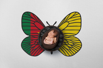 Tiny baby portrait with wings in color of national flag. Newborn photography concept. Cameroon