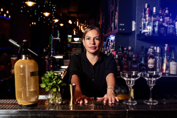 Latina prepares a cocktail at a bar counter. job waitress profession