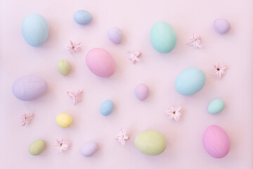 Background for Easter. Easter eggs and delicate pink flowers are laid out on a light background. Chicken eggs and quail eggs. The eggs are painted in soft pastel colors. Postcard, background for