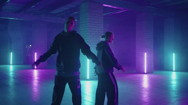 Professional Hip Hop break dancers . Stylish young couple dancing with real strobe lights . Against blue background of led lights. Dancing young couple in colourful neon studio light, hip hop dancers