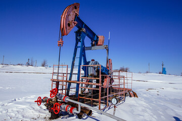 Oil well with oil pump in winter sunny day