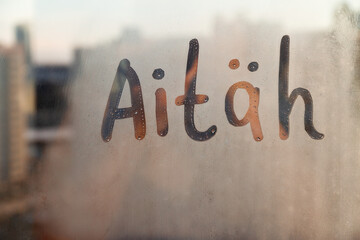 Estonian word Aitah thanks in english are painted on wet orange sunrise glass of window
