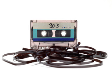 This shows a well known problem with the old fashioned compact cassettes: the tape used to come out, making the cassette useless. Vintage compact cassette tape on white background.
