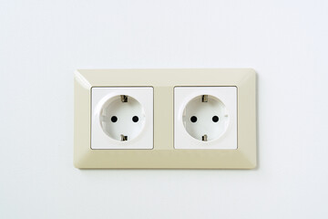 Electric socket on white wall. Double white plastic power outlet.